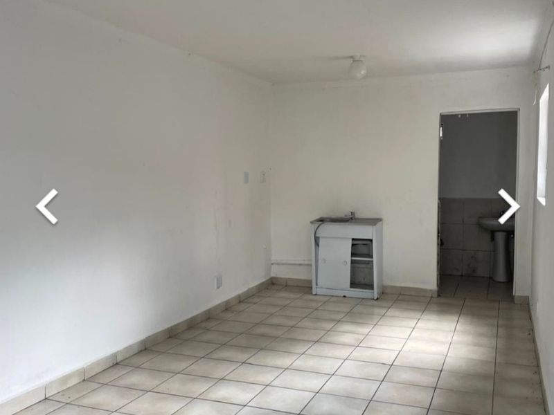 A basic, empty kitchen area featuring tiled flooring and a small sink unit, requiring cosmetic updates and refurbishment to improve its functionality and appeal.