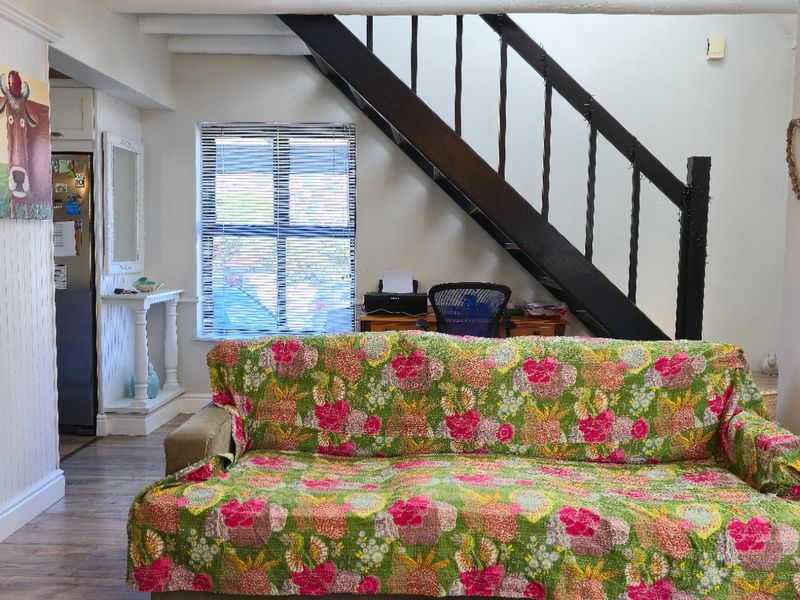 A living room area featuring a staircase, wooden flooring, and exposed ceiling beams, providing a functional and open layout.