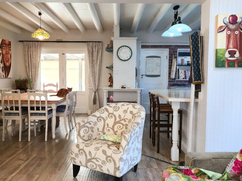 Open plan living and dining area featuring exposed beam ceilings, a breakfast bar, and direct access to the outdoor space through french doors.