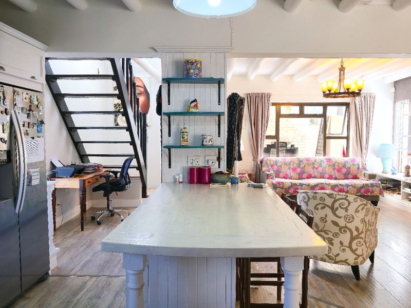 Open-plan living area featuring a central kitchen island, exposed ceiling beams, and a staircase, creating a versatile and connected home layout.