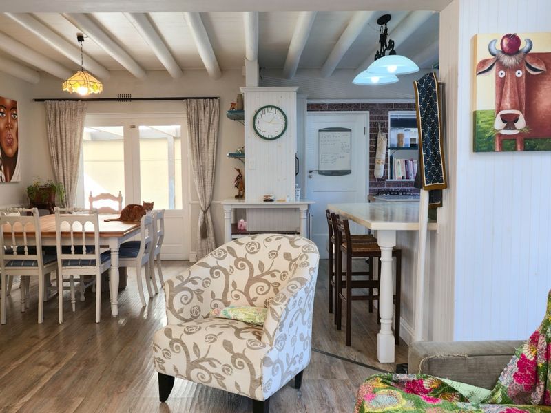 Open-plan living and dining area featuring exposed ceiling beams, beadboard wall paneling, and a breakfast bar connecting to the kitchen space.