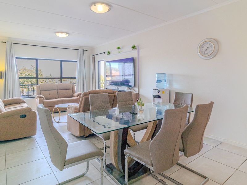 Spacious open-plan living and dining area featuring tiled flooring, large windows, and direct access to a balcony.