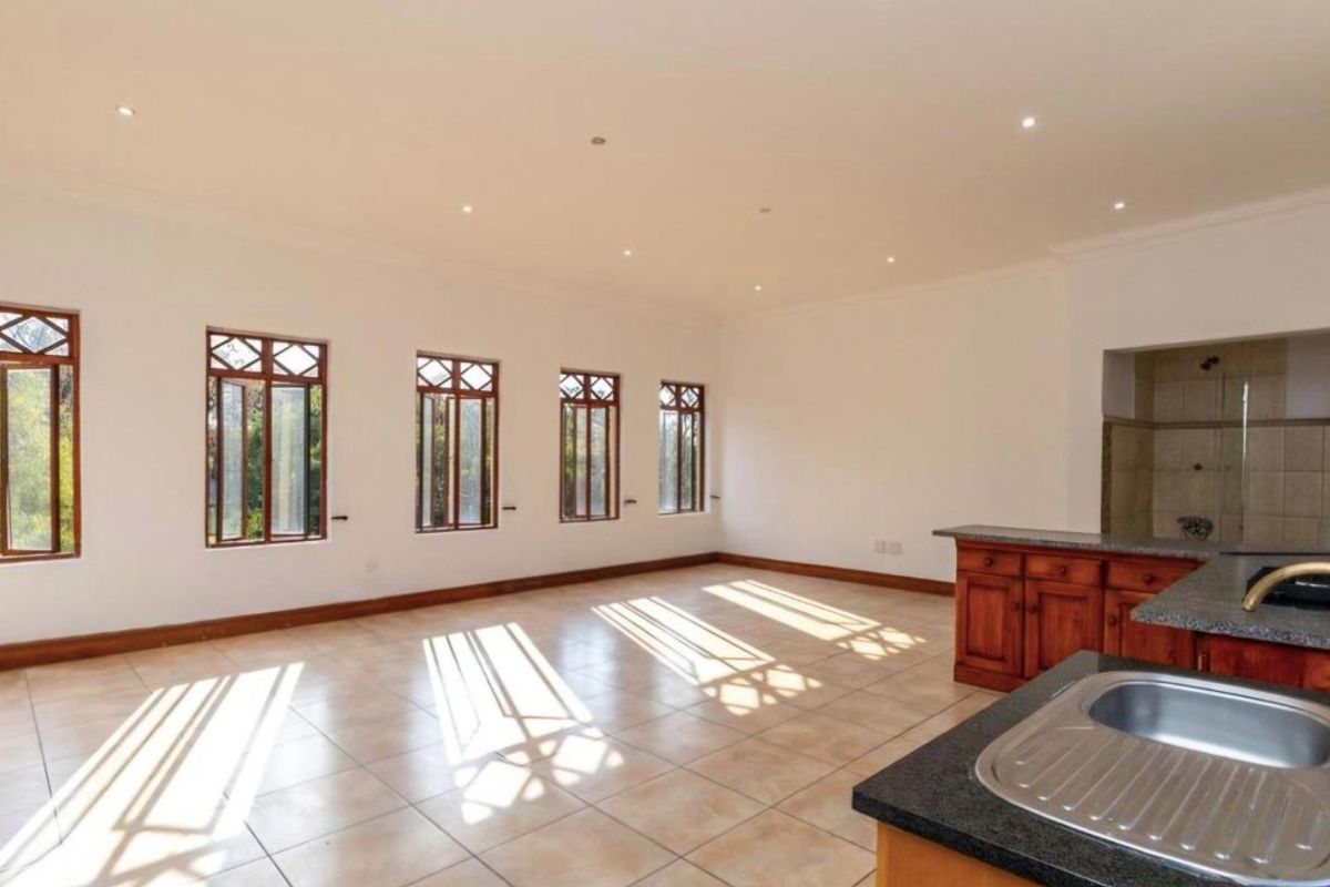 Spacious open-plan living area featuring tiled floors, recessed lighting, and a functional kitchen with granite countertops and timber cabinetry.