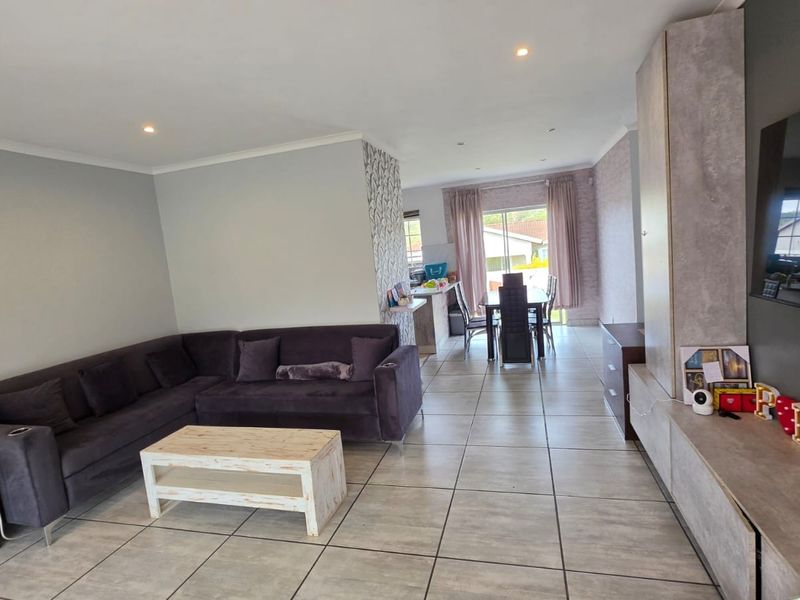 Spacious open-plan living and dining area featuring neutral tiled flooring, recessed lighting, and a modern built-in media unit.