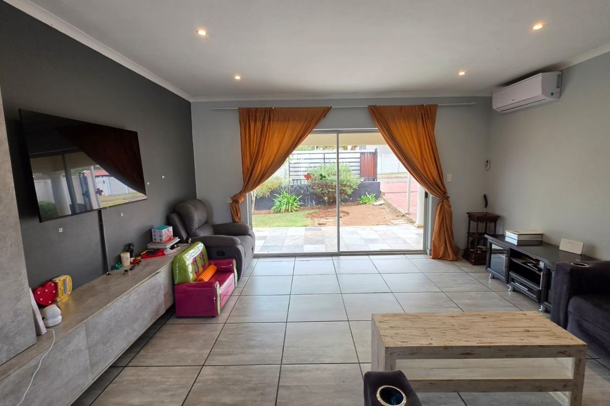Spacious living room featuring large format floor tiles, a feature wall, and direct access to the rear patio through sliding glass doors.