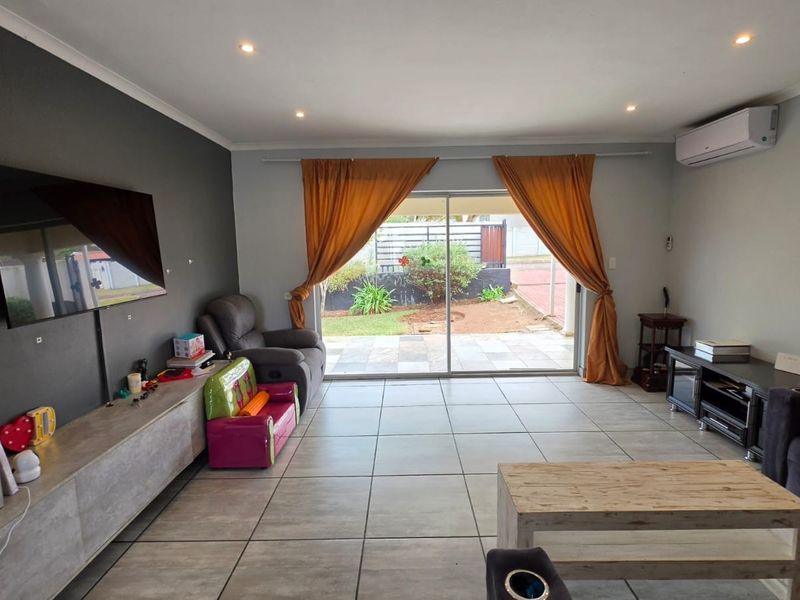 Spacious living room featuring large format floor tiles, a feature wall, and direct access to the rear patio through sliding glass doors.