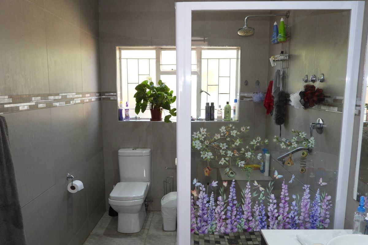 A functional bathroom featuring a walk-in shower with glass enclosure, modern toilet, and tiled finishes throughout.