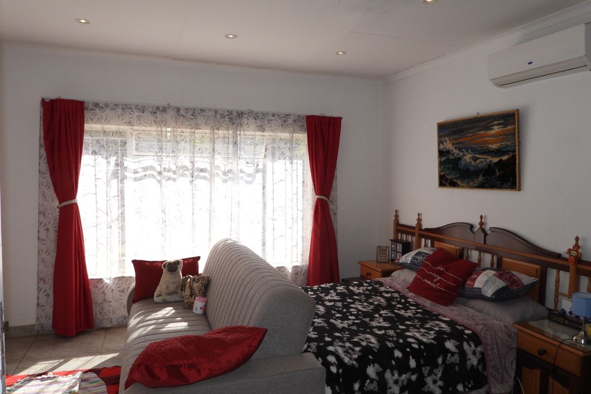 Spacious bedroom featuring tiled flooring, recessed downlighting, and a wall-mounted split-system air conditioning unit.