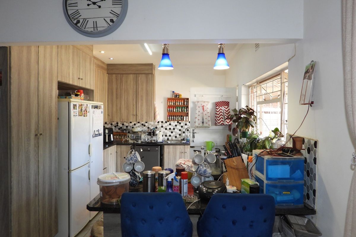A functional kitchen featuring wood-look cabinetry, a modern hexagonal tile backsplash, and a breakfast bar area with pendant lighting.