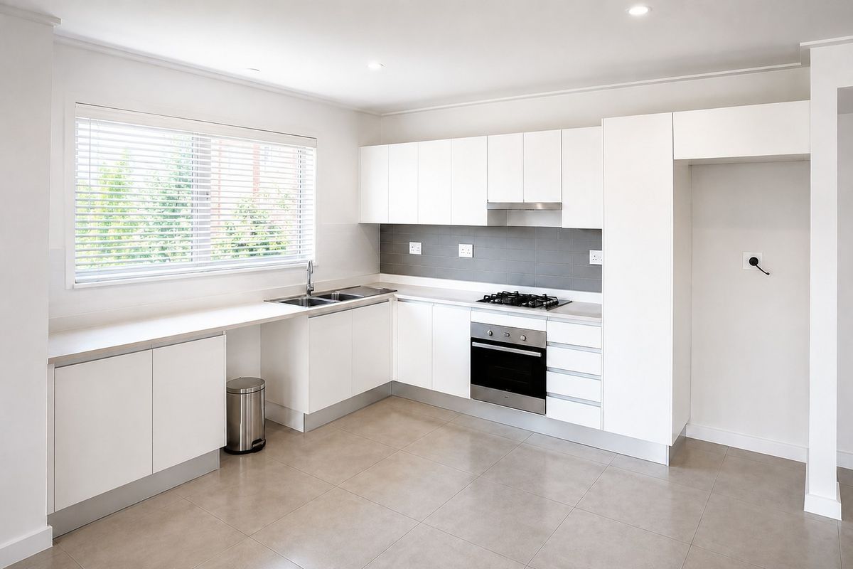 Modern, clean-lined kitchen featuring white cabinetry, integrated stainless steel appliances, gas hob, and neutral tiled flooring in a bright, open-plan layout.