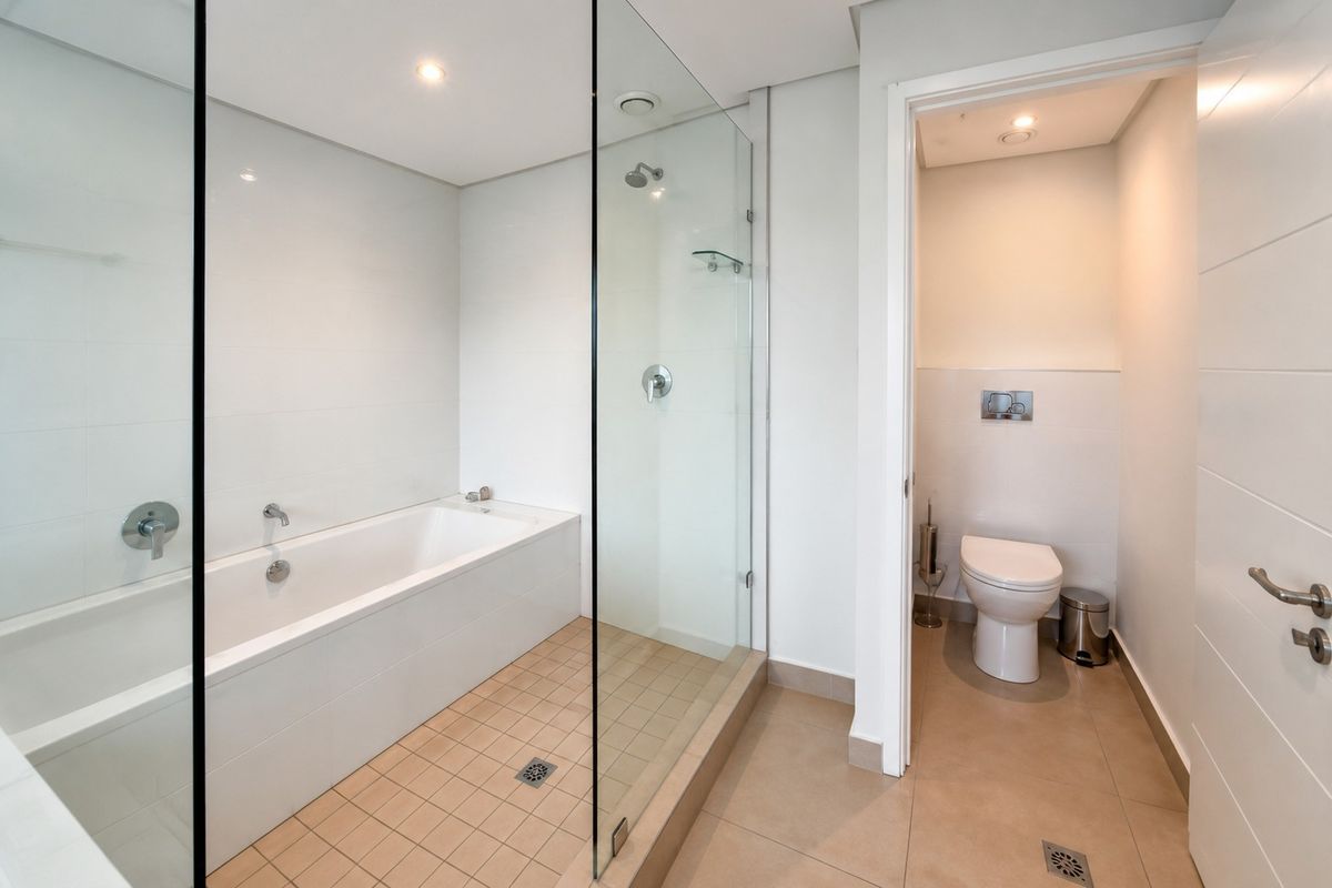 Modern bathroom featuring a built-in bathtub, separate glass-enclosed shower, and a private toilet area with a wall-hung unit.
