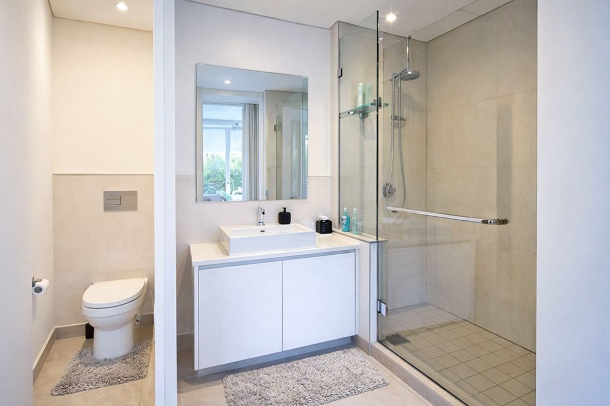 Modern bathroom featuring a wall-mounted toilet, sleek vanity with vessel sink, and a spacious walk-in shower with a glass enclosure.