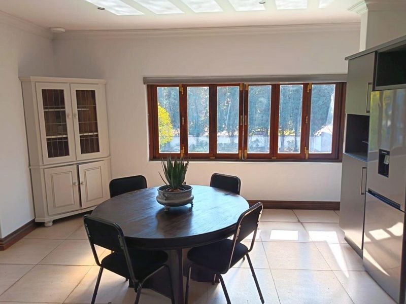 A bright dining area featuring tiled flooring, wooden window frames, and recessed ceiling lighting, offering a clean and functional space.