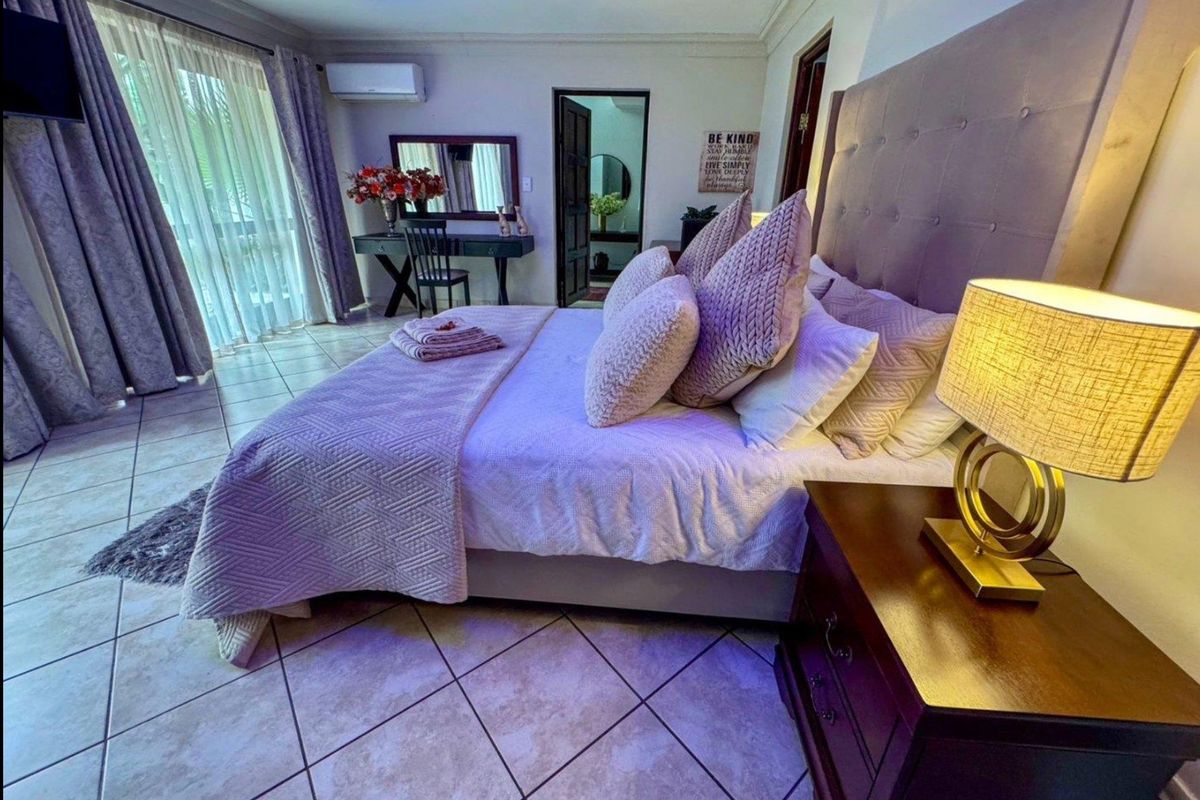 Spacious bedroom featuring tiled flooring, a wall-mounted air conditioning unit, and large sliding glass doors providing access to the exterior.