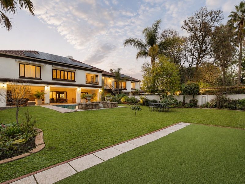Spacious rear garden featuring a swimming pool, covered patio area, and well-maintained landscaping, set against the rear elevation of the two-story residence.
