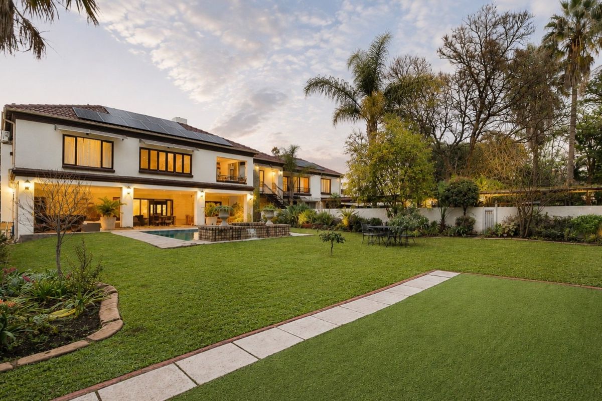 Spacious rear garden featuring a swimming pool, covered patio area, and well-maintained landscaping, set against the rear elevation of the two-story residence.