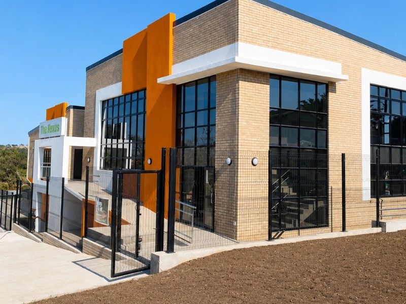 Modern office building exterior featuring brick cladding, large glass windows, and a concrete accessibility ramp with secure perimeter fencing.