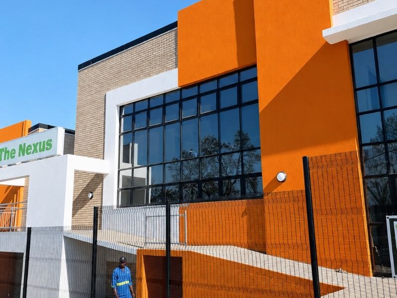 Modern office building exterior featuring bold orange accents, large glass windows, and a concrete accessibility ramp.