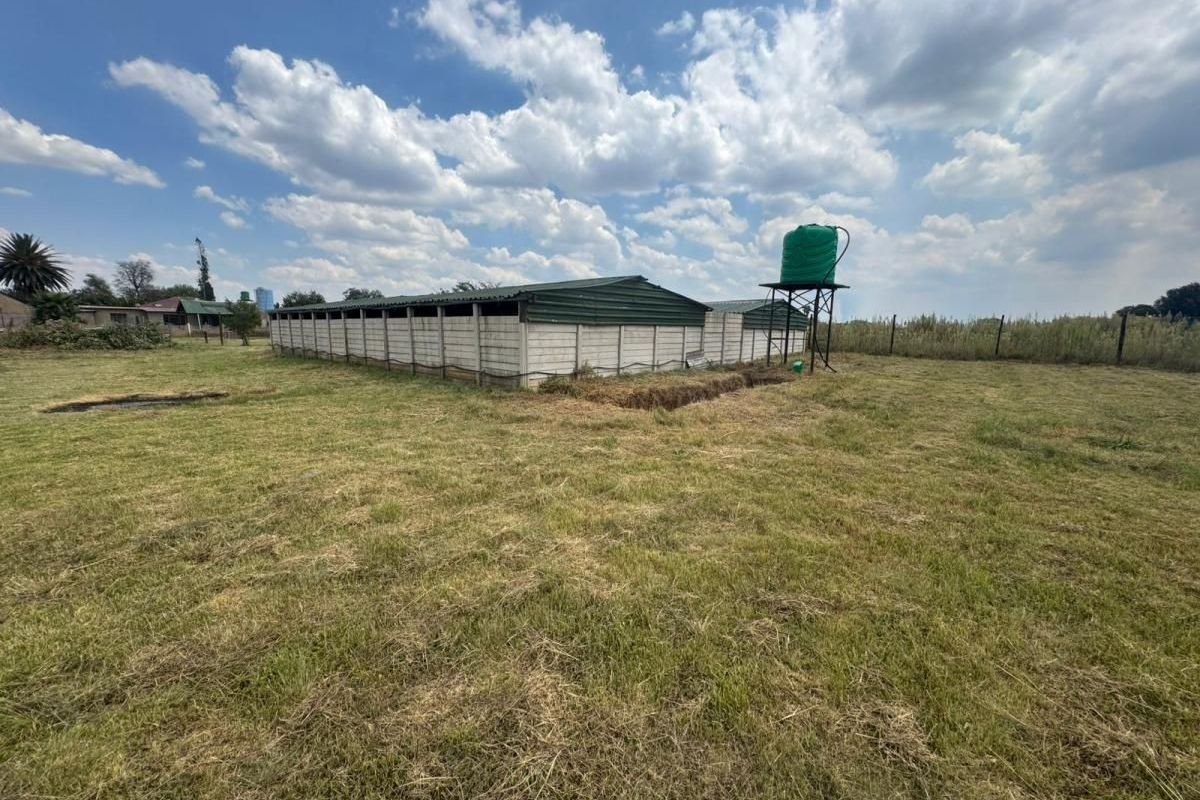 A view of the farm property featuring a large agricultural outbuilding with a metal roof and an elevated water storage tank.