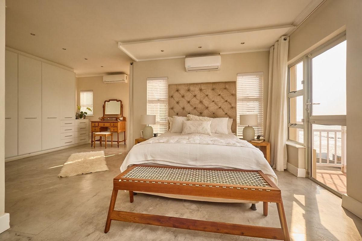 Spacious bedroom featuring built-in cupboards, air conditioning, and direct access to a private balcony through sliding glass doors.