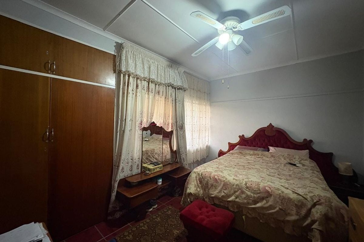 A bedroom featuring tiled flooring, a ceiling fan, and a built-in wooden wardrobe.
