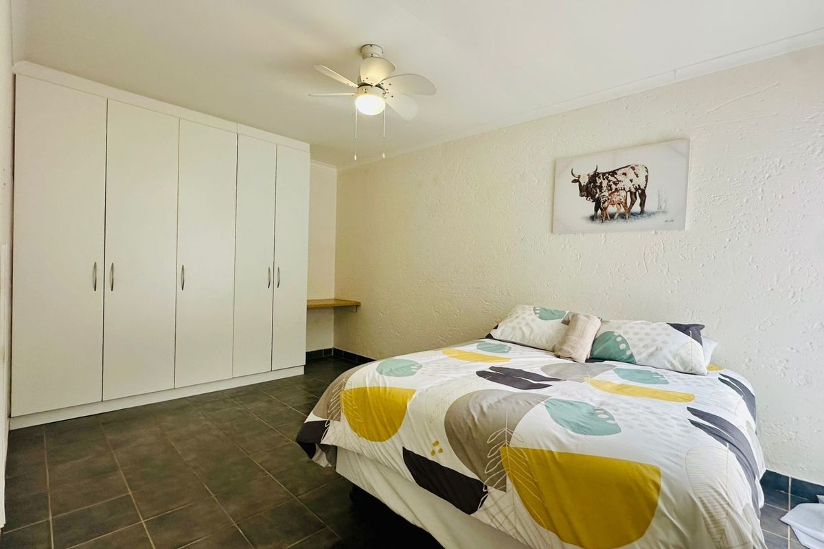 A bedroom featuring built-in cupboards, a ceiling fan, and tiled flooring, providing functional storage and comfortable living space.