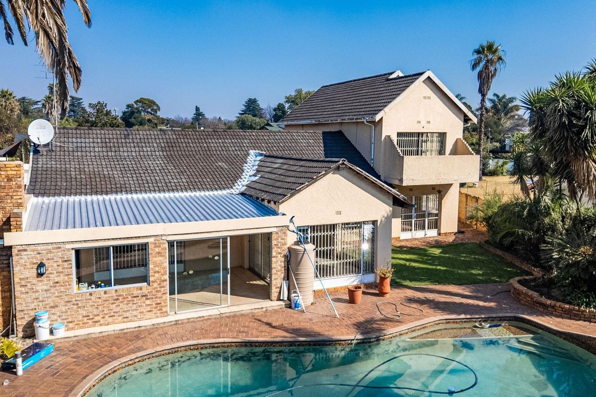 Aerial view of a multi-level residential property featuring a swimming pool, paved patio area, and a combination of brick and rendered exterior finishes.