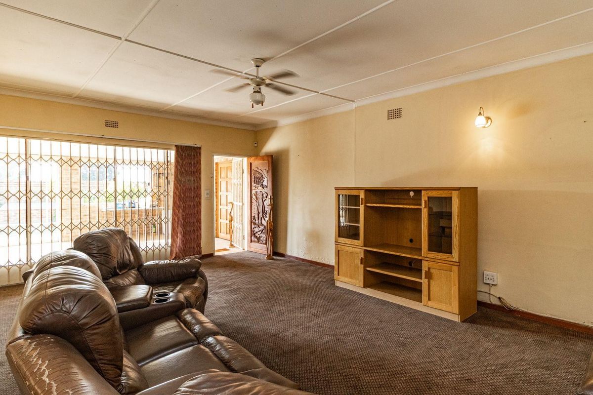Spacious living room featuring a ceiling fan, wall sconces, and a security gate leading to the exterior.