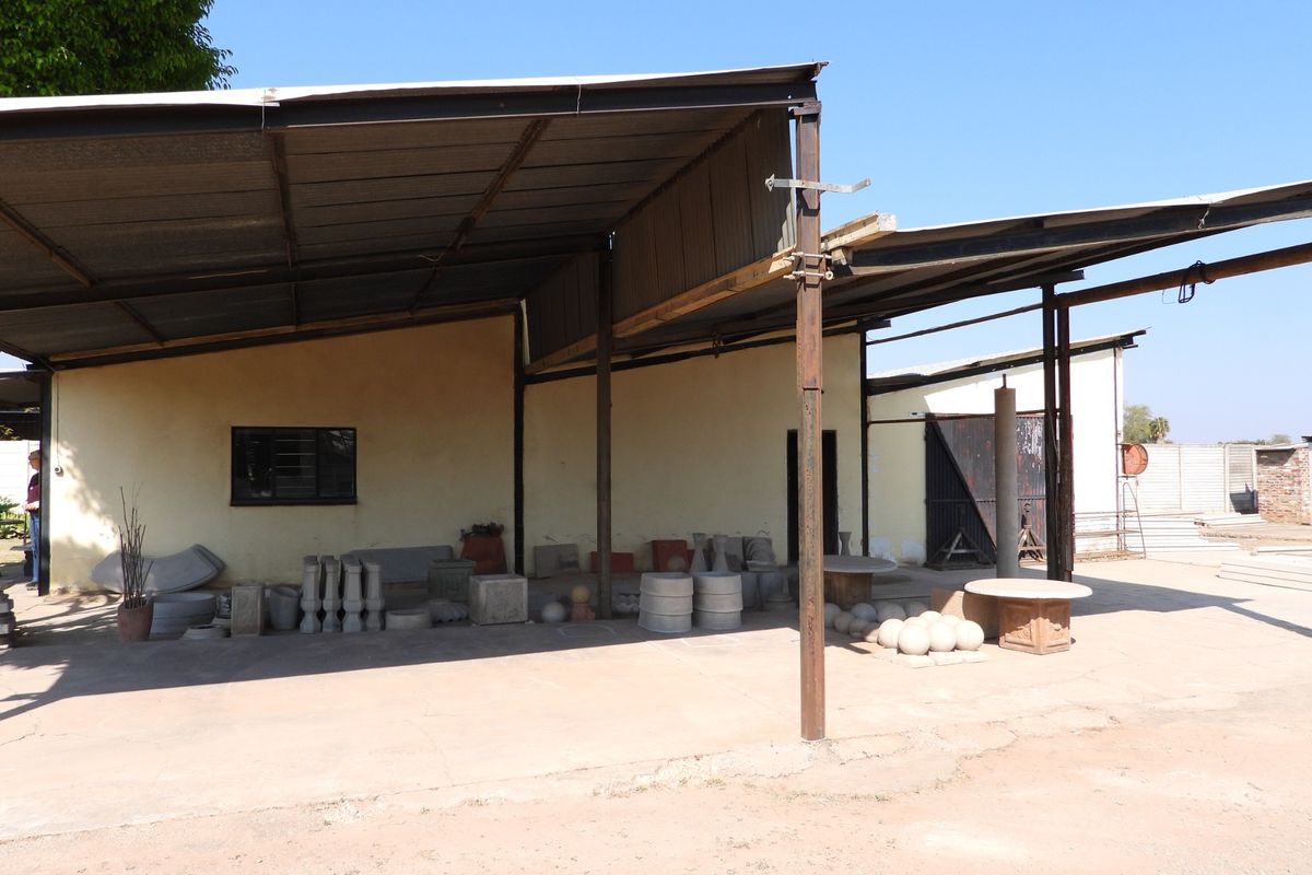 A large, open-sided utility or workshop area featuring a corrugated metal roof supported by steel columns and a concrete floor.