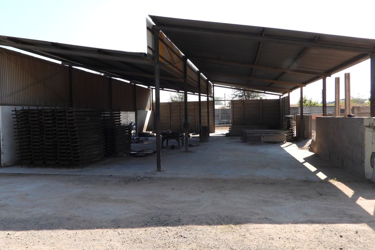 A large, open-plan utility or industrial storage space featuring a corrugated metal roof, steel support columns, and a concrete floor.