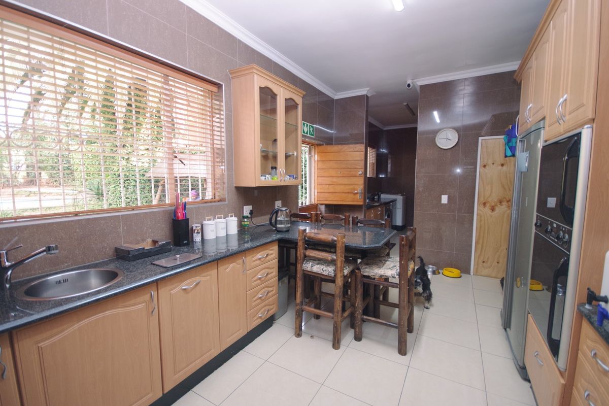 A functional kitchen featuring granite countertops, built-in wooden cabinetry, and tiled finishes, offering a practical layout with integrated oven and ample storage space.
