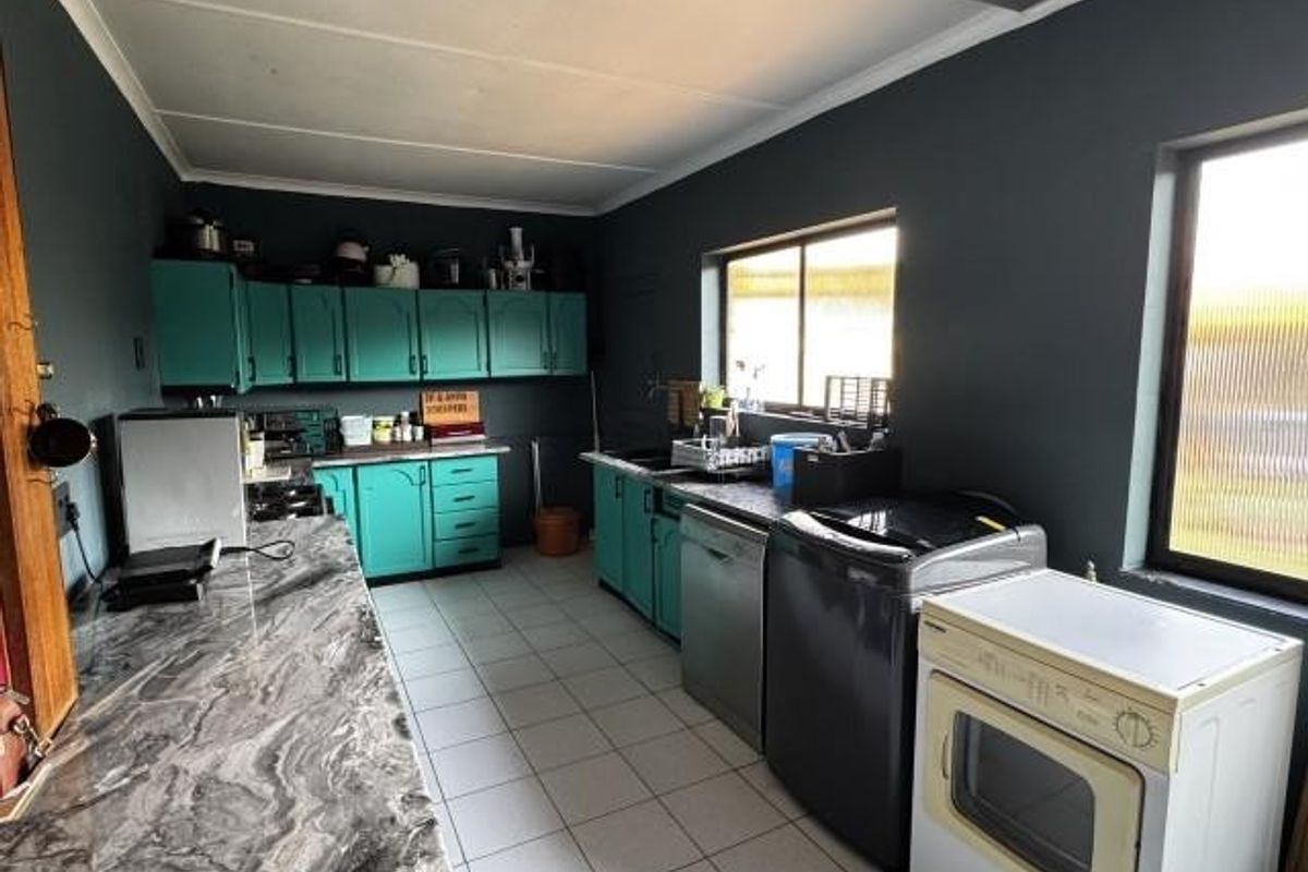 A functional kitchen featuring dark-painted walls, ample built-in cabinetry, laminate countertops, and tiled flooring, offering a practical layout for daily use.