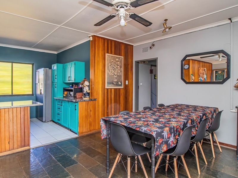 Open-plan living and kitchen area featuring slate flooring, wood paneling, and a functional kitchen layout with built-in cabinetry and stone countertops.