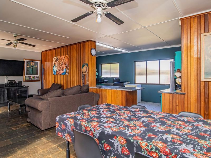 Open-plan living and dining area featuring stone tile flooring, wood paneling, and a breakfast bar connecting to the kitchen space.