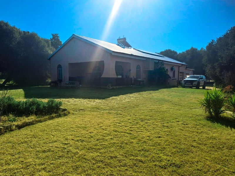 Rear view of the property featuring a covered patio, solar water heating system, and expansive lawn area.