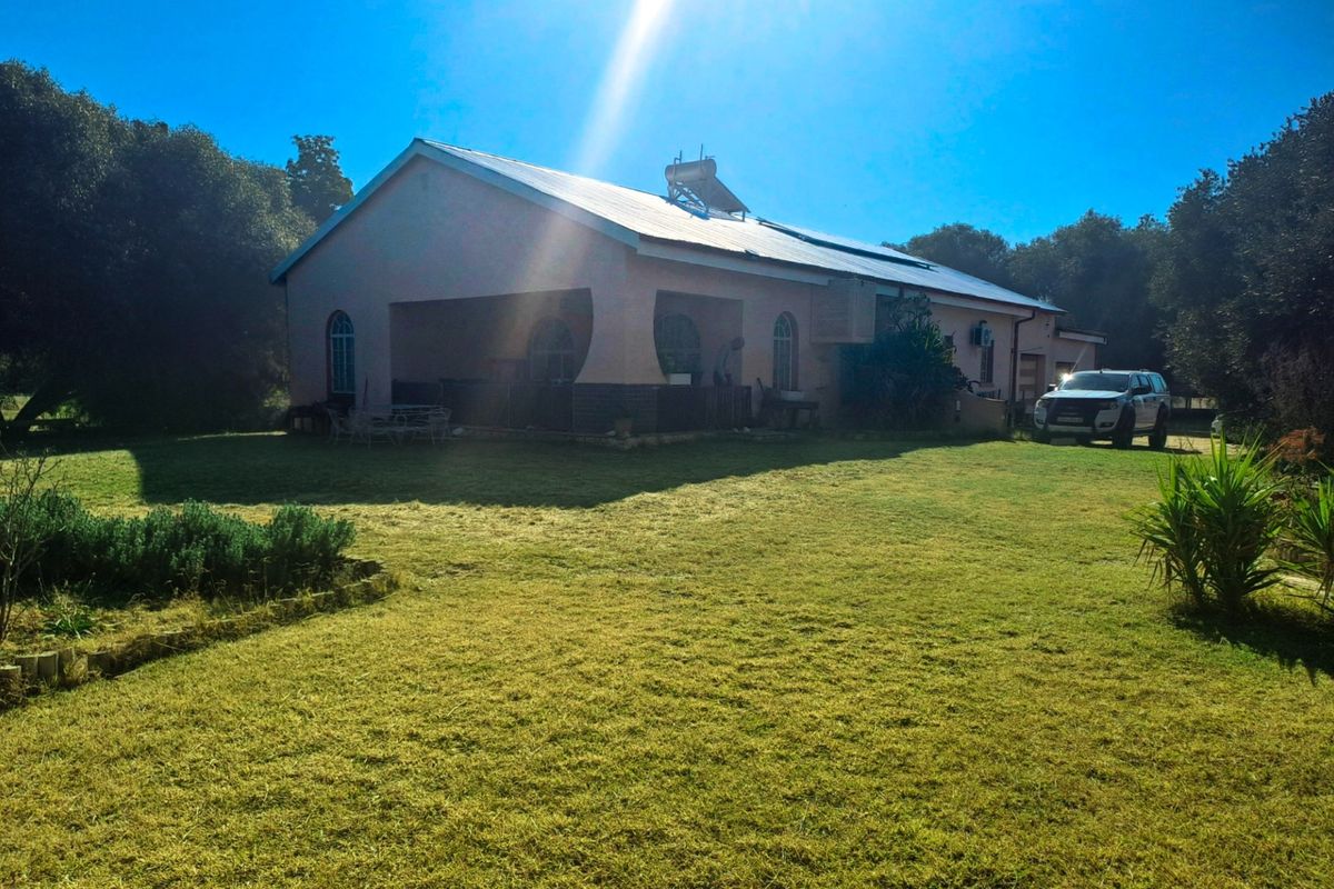 Rear view of the property featuring a covered patio, solar water heating system, and expansive lawn area.