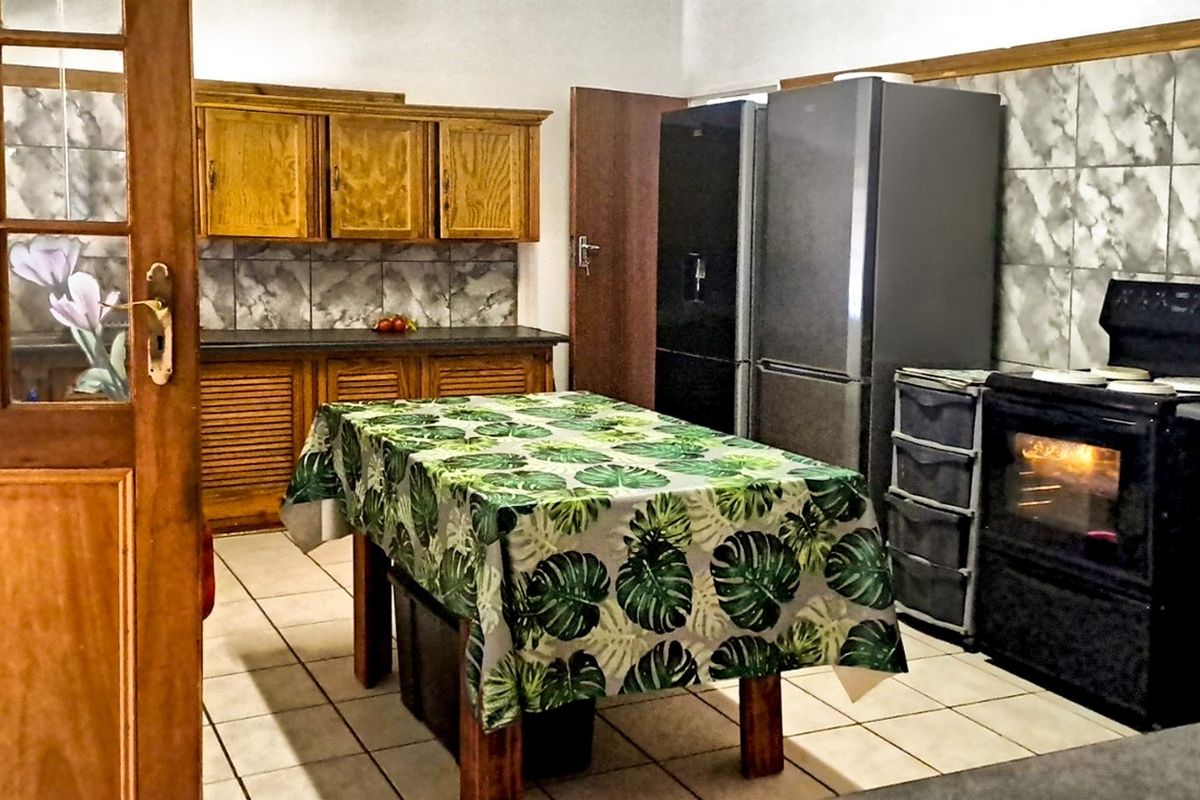 A functional kitchen featuring wooden cabinetry, tiled backsplash, and tiled flooring, providing a traditional layout with built-in cooking appliances.