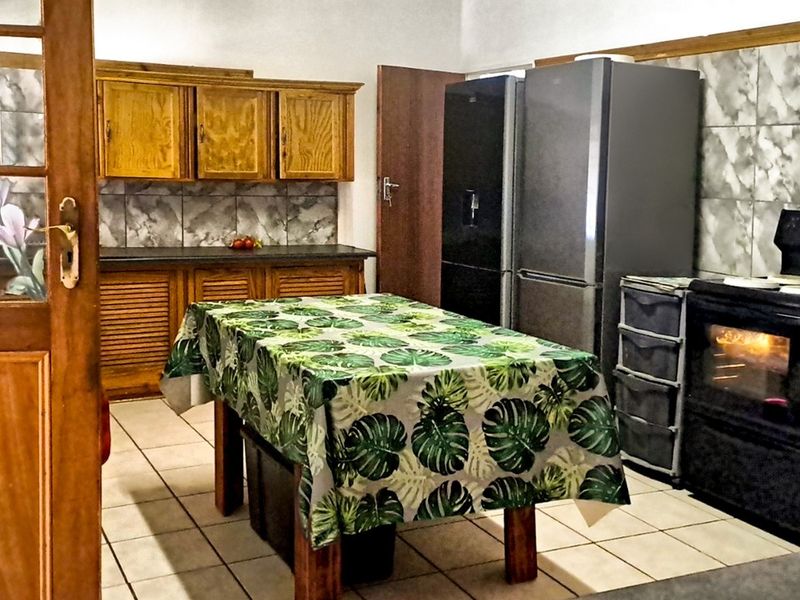 A functional kitchen featuring wooden cabinetry, tiled backsplash, and tiled flooring, providing a traditional layout with built-in cooking appliances.