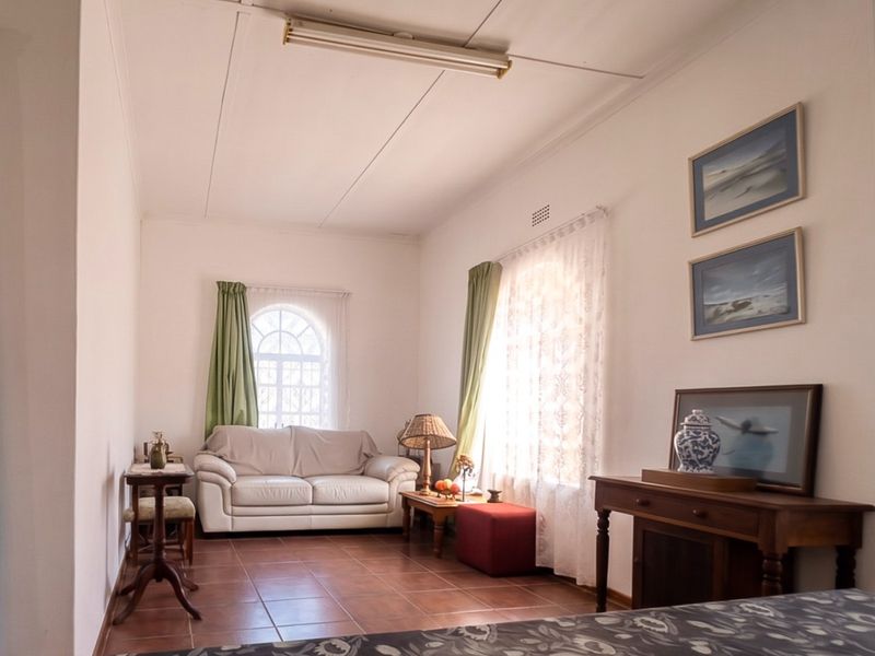 A living room featuring tiled flooring, an arched window, and a standard fluorescent light fixture.