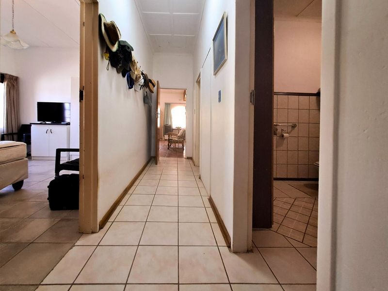 A functional hallway with tiled flooring providing access to adjacent rooms, including a bathroom with tiled wall finishes.