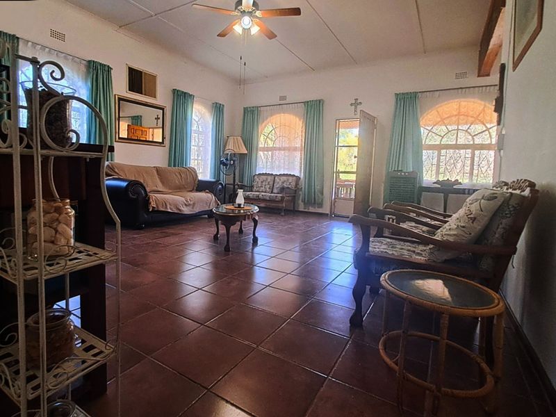 Spacious living room featuring tiled flooring, arched windows, and a ceiling fan, offering a bright and traditional layout.