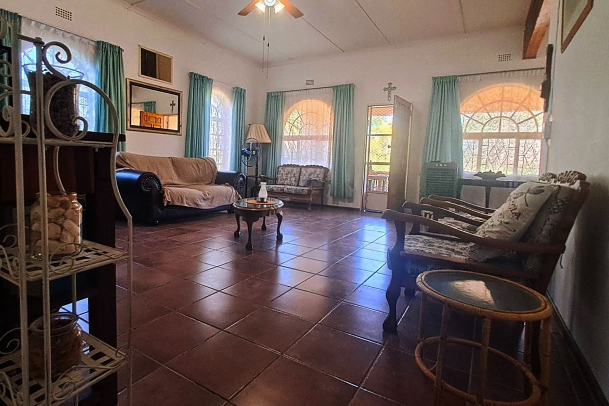 Spacious living room featuring tiled flooring, arched windows, and a ceiling fan, offering a bright and traditional layout.