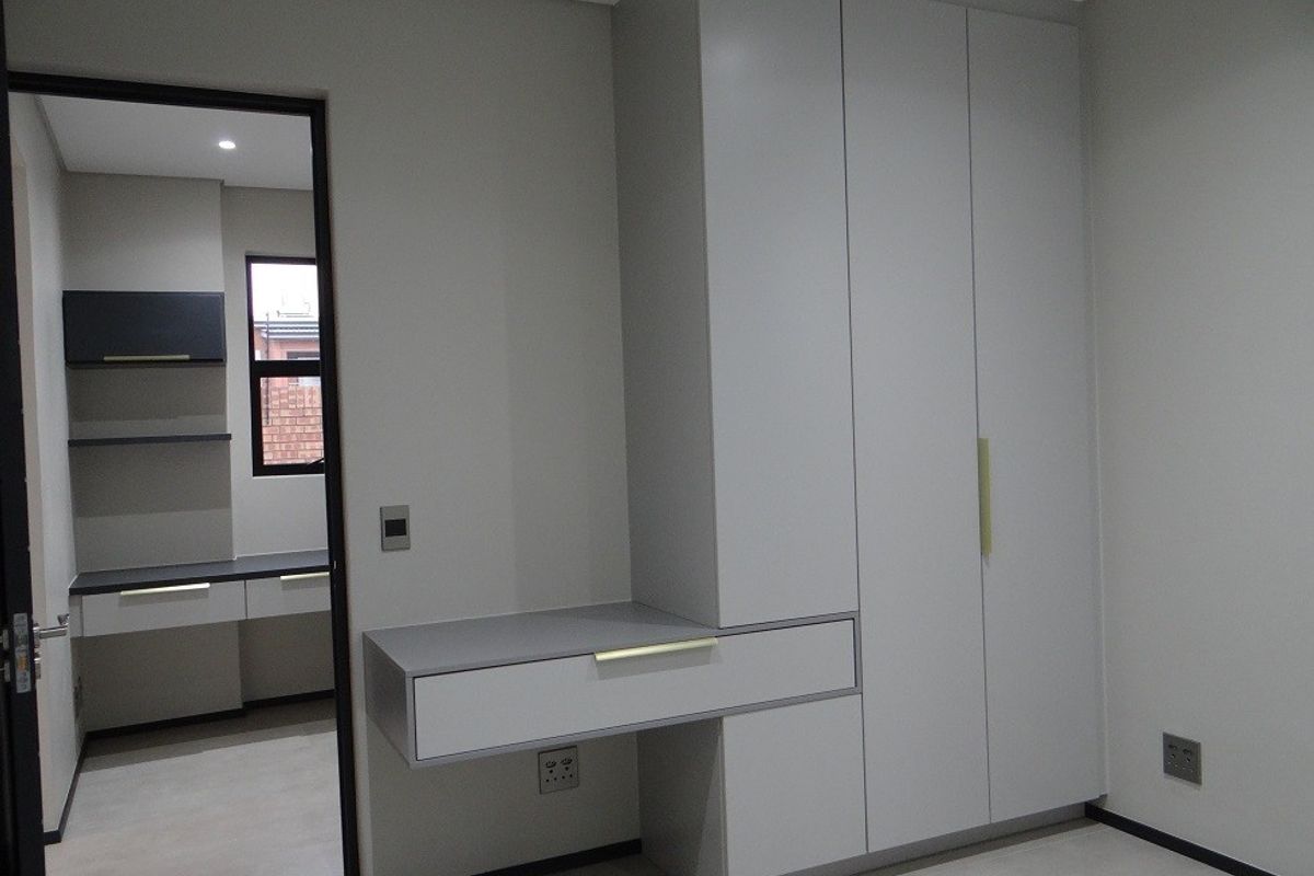 Modern bedroom featuring a sleek built-in wardrobe and integrated desk, with neutral finishes and clean lines throughout.