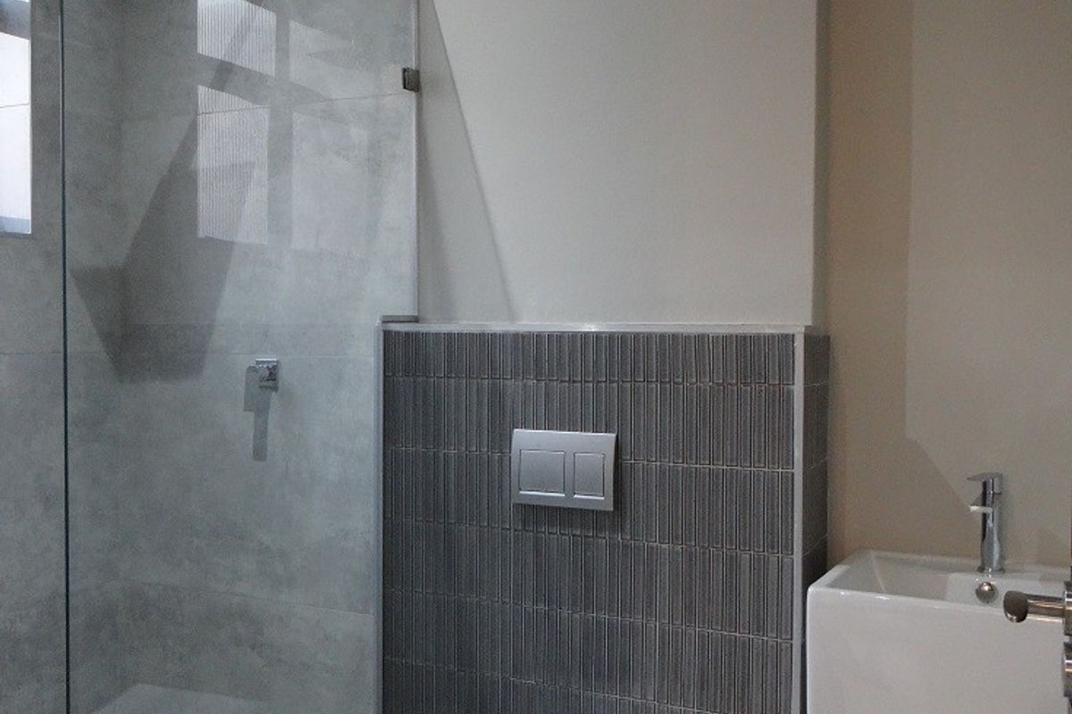 Modern bathroom featuring a walk-in shower with glass screen, wall-hung toilet with concealed cistern, and a sleek freestanding basin.