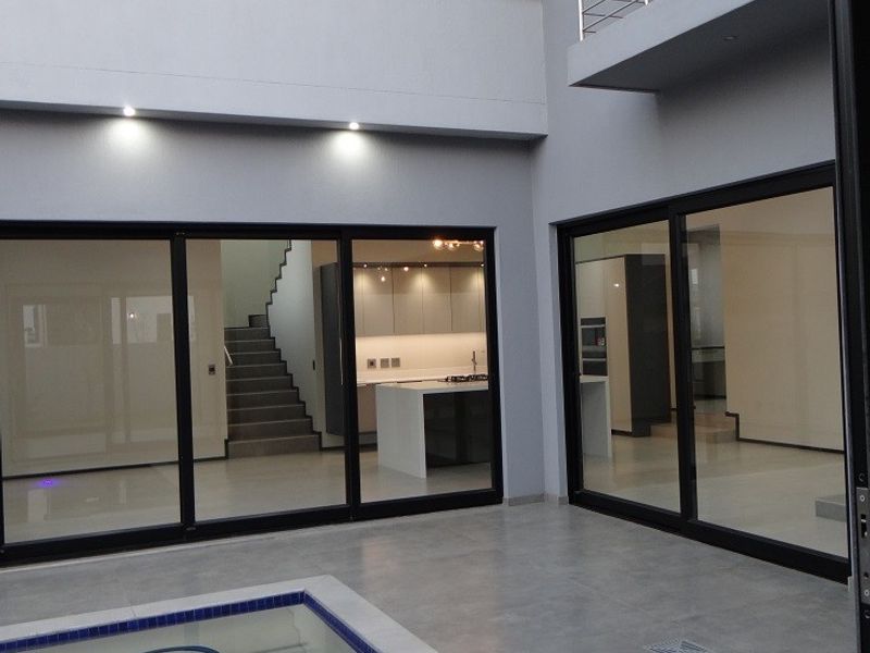 Modern covered patio area featuring tiled flooring, recessed lighting, and a swimming pool, with large sliding glass doors providing access to the interior.