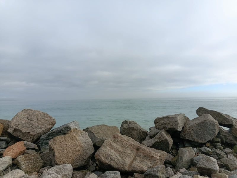 A scenic view of the ocean coastline featuring large natural rock formations along the shore.