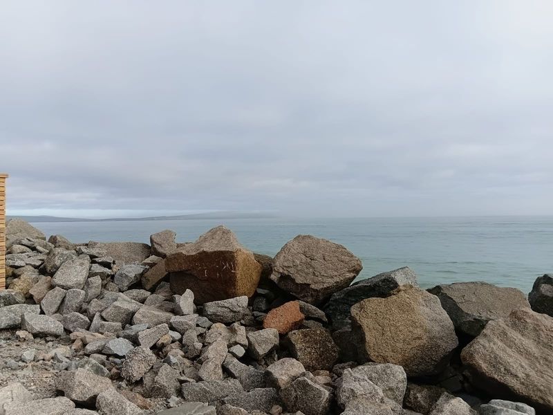 A scenic view of the ocean coastline featuring a natural rock embankment and expansive water horizon.
