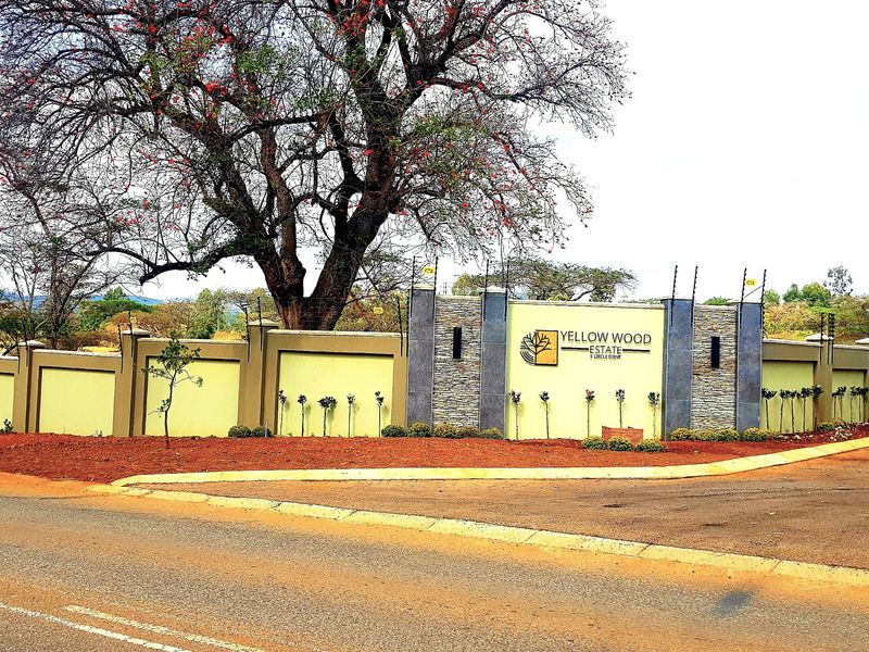 The entrance to Yellow Wood Estate featuring a well-maintained perimeter wall with stone cladding, electric fencing, and prominent estate signage.