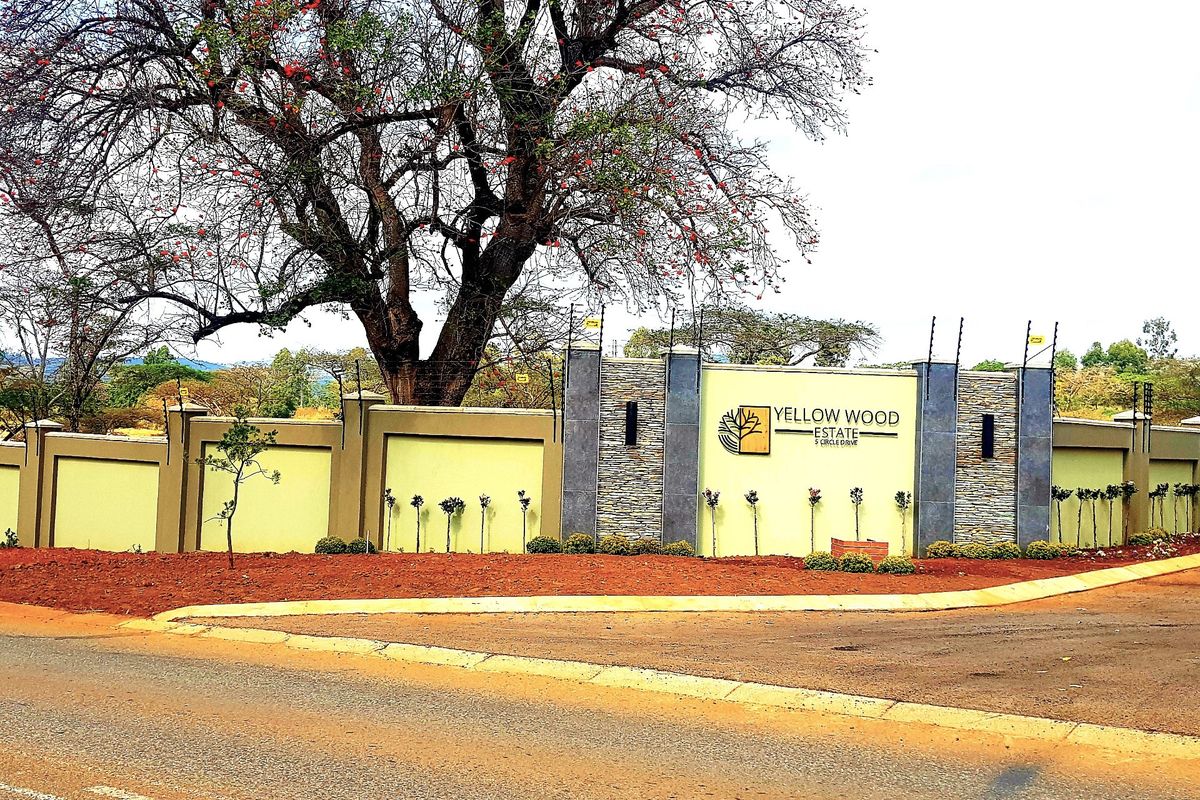 The entrance to Yellow Wood Estate featuring a well-maintained perimeter wall with stone cladding, electric fencing, and prominent estate signage.