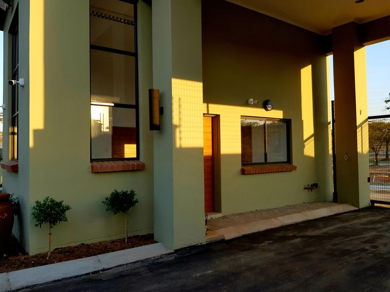 Front facade of a modern residential property featuring a paved driveway, security lighting, and brick-accented window sills.